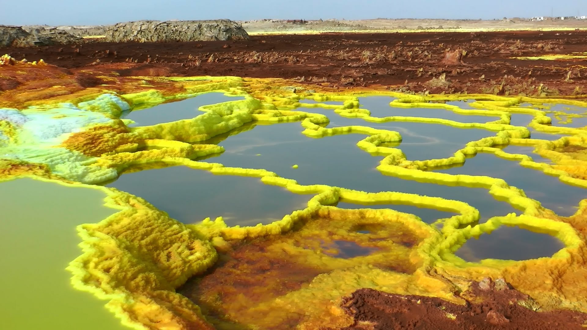 Another vivid view of Dallol's patterned mineral pools and terraces.