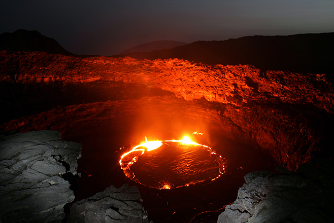 Erta Ale lava lake glowing deep inside the crater at night.