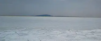 A broad view of the white salt plain stretching to the horizon.